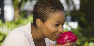 woman smelling flower in her garden