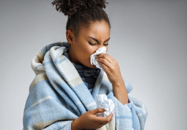 Throat Pain and Headaches woman sneezing with common cold