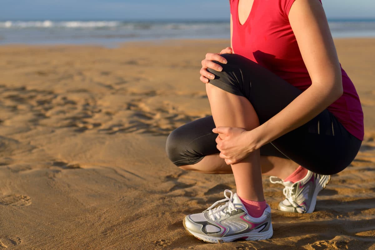 Runner's Guide to Prevent Pain runner with painful shin splints on the beach