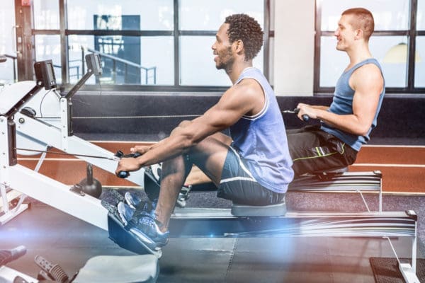 Two men on rowing machines in gym fitness trend