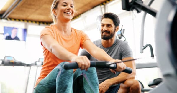 Woman and man on rowing machines fitness trend
